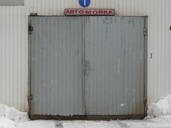 Worn grey metal doors with lined texture on surface and peeling paint.